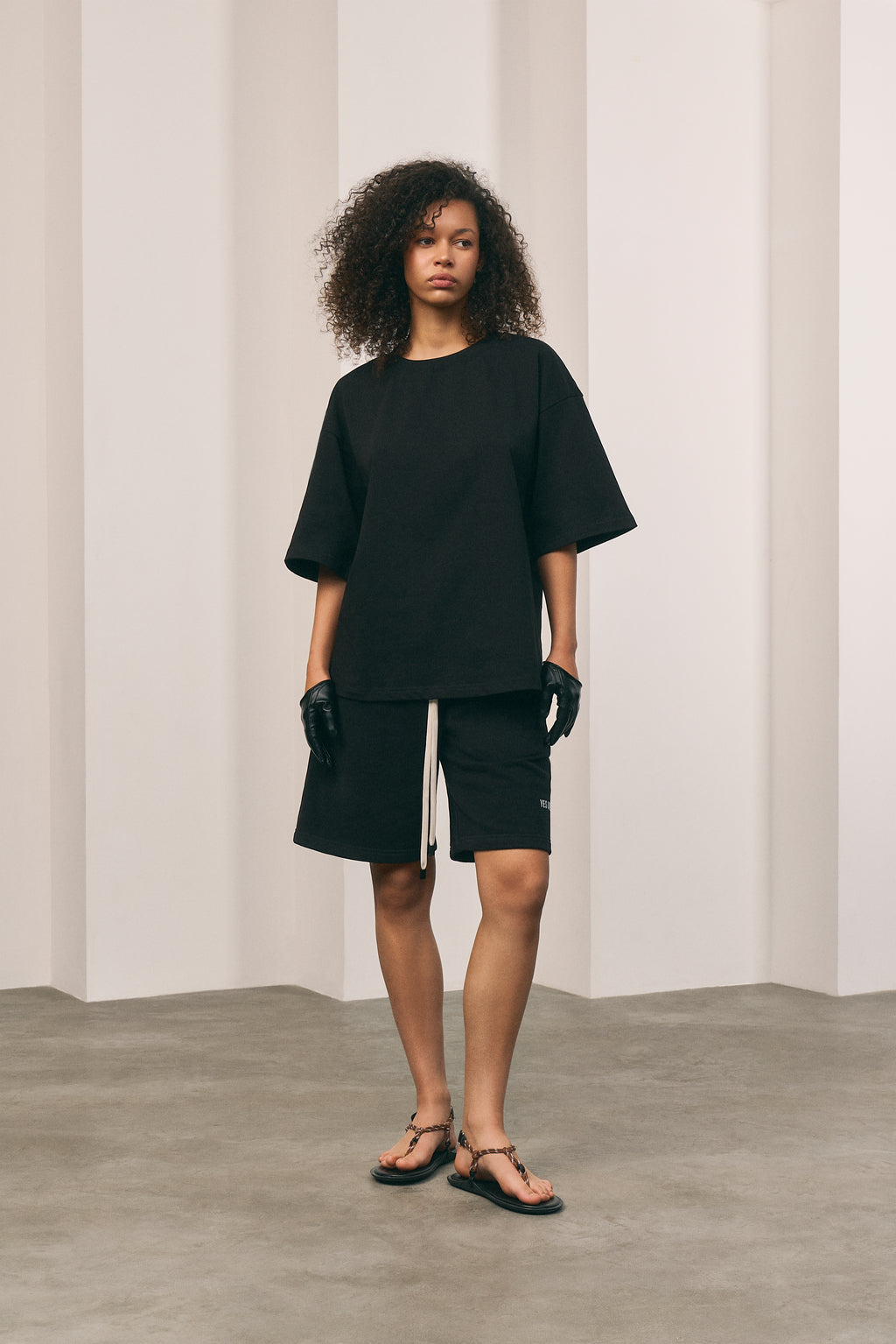Person wearing a black outfit standing against a plain background