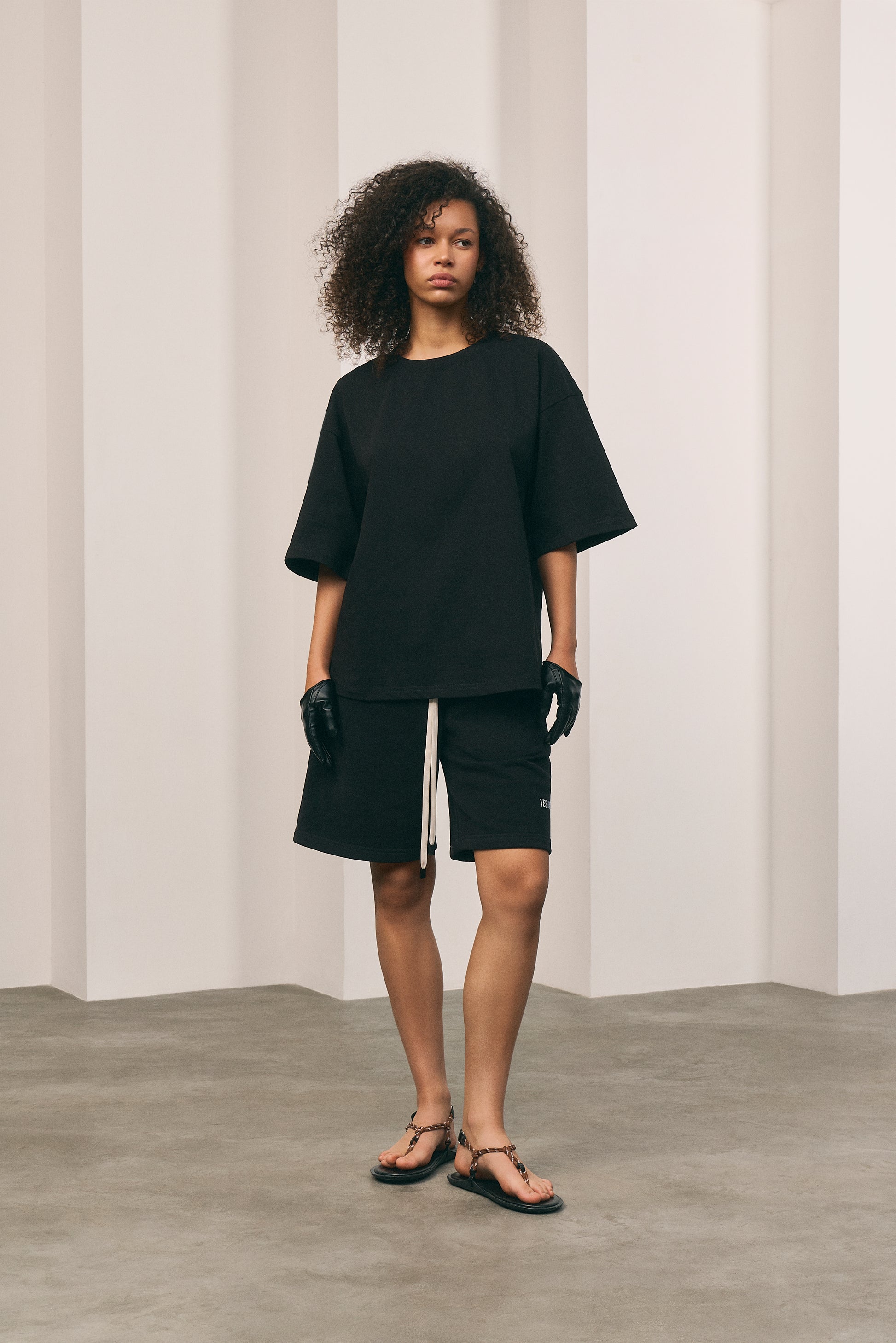 Person wearing a black outfit standing against a plain background